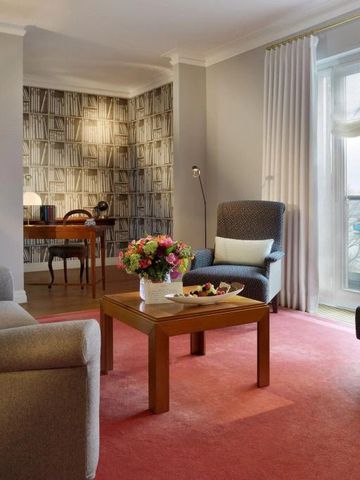 Luxuriöses Hotelzimmer mit Sitzecke, Schreibtisch und großem Fenster.