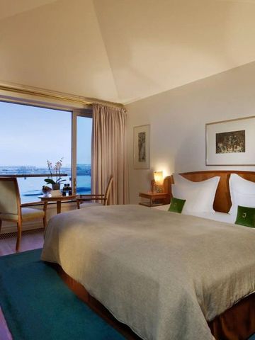 Stilvoll eingerichtetes Hotelzimmer mit Panoramablick und komfortablem Bett.