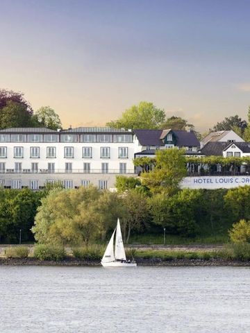 Hotelansicht von der Elbe aus mit Boot und grüner Umgebung
