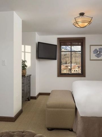 Geräumiges Hotelzimmer mit einem großen Bett und Blick auf den Berg durch das Fenster