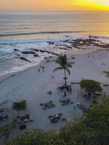Sonnenuntergang am Strand mit Palmen und sanften Wellen.