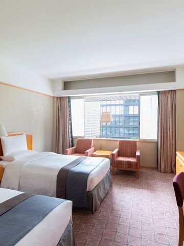 Modernes Hotelzimmer mit zwei Einzelbetten und Sitzecke im The Okura Tokyo
