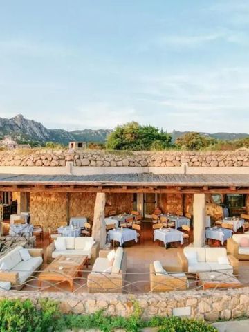 Gemütlicher Außenbereich eines Restaurants mit Bergblick und Steinwänden.