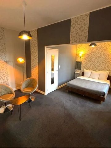 Elegantes Zimmer mit Doppelbett, zwei Sesseln und stilvollen Tapeten.