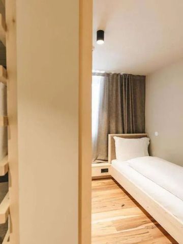 Modernes Einzelzimmer mit Holzboden und großer Dusche im Hintergrund