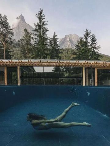 Frau schwimmt im modernen Außenpool mit Bergblick