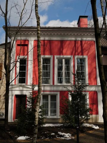 Klassische Fassade eines rosafarbenen Gebäudes mit hohen Fenstern und weißen Säulen.