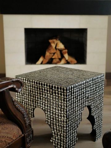 Gemütliche Lounge mit Kamin und stilvollem Tisch aus Mosaikfliesen
