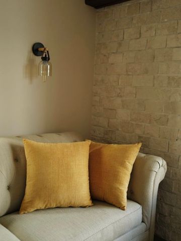 Gemütlicher Sessel mit gelben Kissen und Wandlampe in elegantem Raum