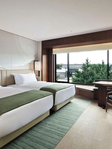 Modernes Hotelzimmer mit zwei Einzelbetten und Blick auf Grünanlagen