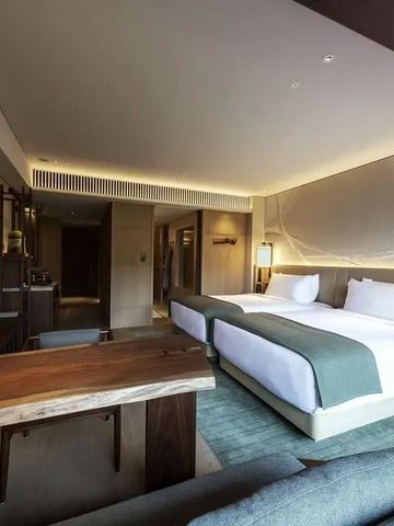 Hotelzimmer mit zwei Betten, Schreibtisch und gemütlicher Beleuchtung.