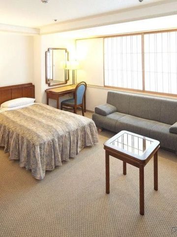 Elegantes Hotelzimmer in neutralen Tönen mit zwei Betten und Sofa