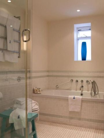 Geräumiges Badezimmer mit Badewanne und heller Fliesenverkleidung. Stilvolle Dekoration.