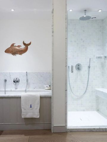Badezimmer mit eleganter Dusche und dekorativem Fischmotiv an der Wand.