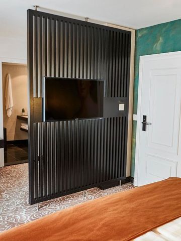 Modernes Hotelzimmer mit stilvoller Trennwand und Flachbild-TV
