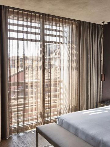 Helles Hotelzimmer mit Vorhängen und Ausblick auf Stadt
