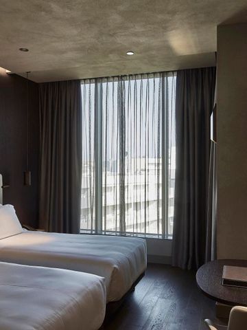 Elegantes Hotelzimmer mit zwei Einzelbetten und großen Fenstern.