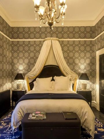 Hotelzimmer mit luxuriösem Baldachinbett und eleganten Kronleuchtern