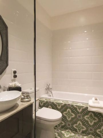 Modernes Badezimmer mit Badewanne, elegantem Waschtisch und dekorativer Fliesenarbeit