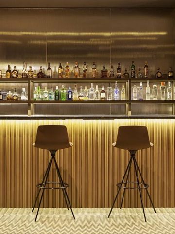 Elegant gestaltete Bar mit moderner Beleuchtung und stilvollen Barhockern