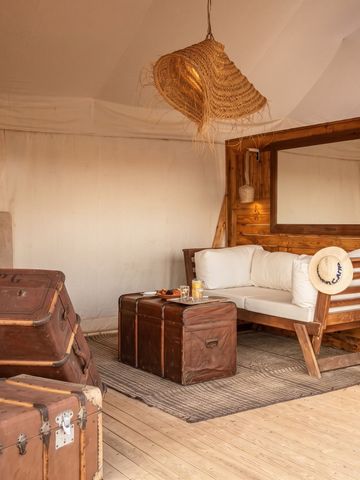 Einladende Sitzecke mit Sofa und rustikalem Koffer im Zelt des Inara Camp.