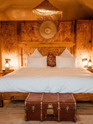 Gemütliches Bett in einem Zeltzimmer mit Holzelementen und weicher Beleuchtung im Inara Camp.