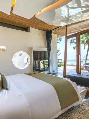 Schlafzimmer mit großem Fenster und direktem Blick auf den Strand und das Meer.