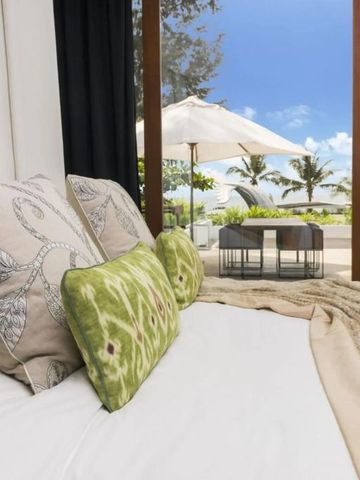 Blick aus dem Schlafzimmer auf eine Terrasse mit Liegen und Palmen im Hintergrund.