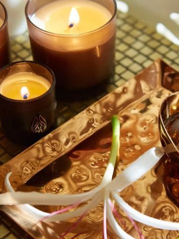 Elegantes Spa-Ambiente mit brennenden Kerzen auf einem Kupfertablett