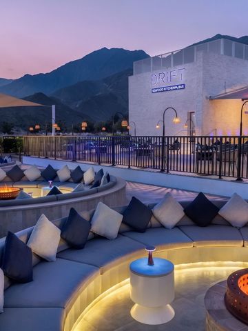 Gemütliche Outdoor-Lounge mit Feuerstellen und Bergblick bei Dämmerung.