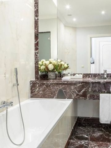 Großzügiges Badezimmer mit eleganter Badewanne und Marmorverkleidung
