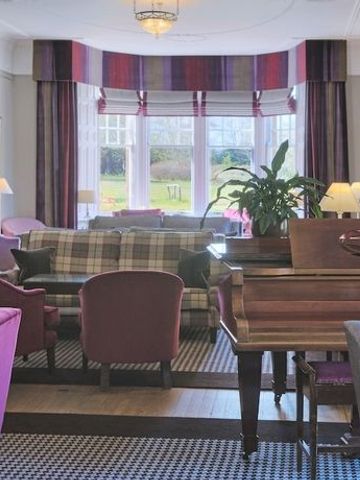 Elegante Hotel-Lounge mit Kamin, bequemen Sofas und Blick auf den Garten