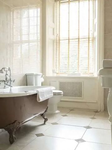 Luxuriöses Badezimmer mit freistehender Wanne und großem Fenster
