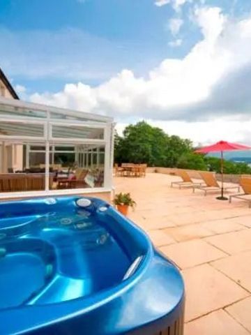 Terrasse mit Whirlpool und Sonnenliegen unter blauem Himmel