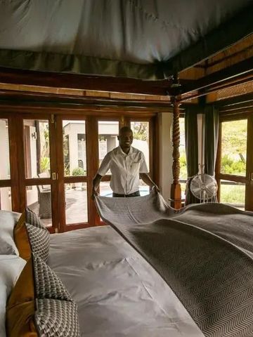 Hotelmitarbeiter beim Herrichten eines eleganten Bettes in einer luxuriösen Suite.