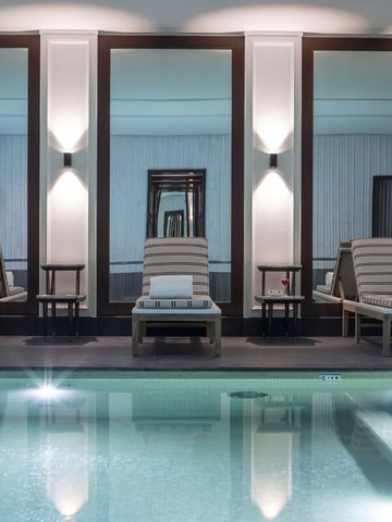 Innenpool mit eleganten Liegen und Spiegeln im J.K. Place Paris