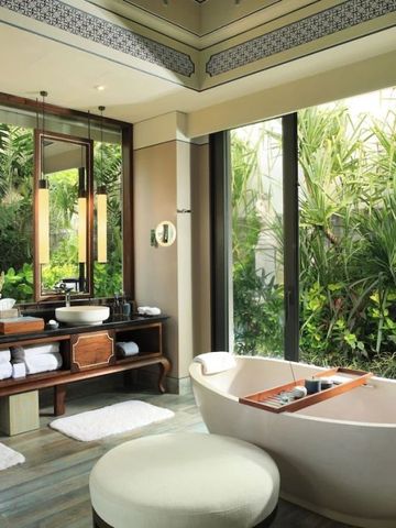 Badezimmer mit großen Fenstern zur Gartenansicht und einer eleganten Badewanne