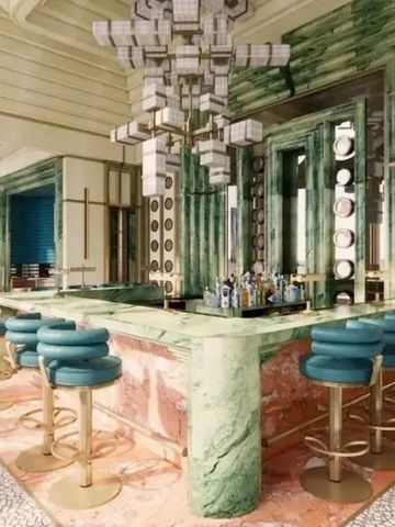 Elegante Bar mit grünen Marmorelementen und blauen Barhockern