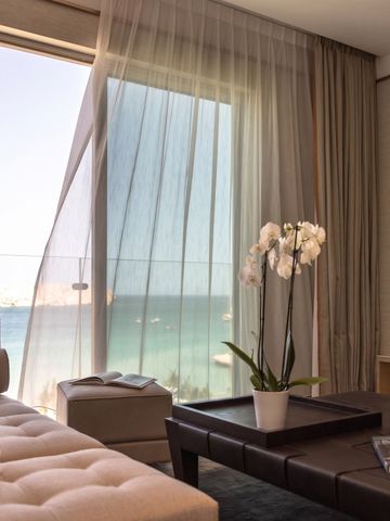 Luxuriöses Zimmer mit Meerblick. Elegantes Sofa und luftige Vorhänge.