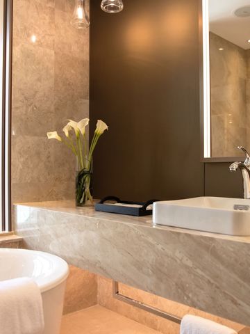 Badezimmer mit Steinwaschbecken und luxuriöser Badewanne.