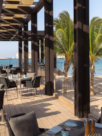 Strandrestaurant mit Blick auf Palmen und das Meer im Jumeirah Muscat Bay