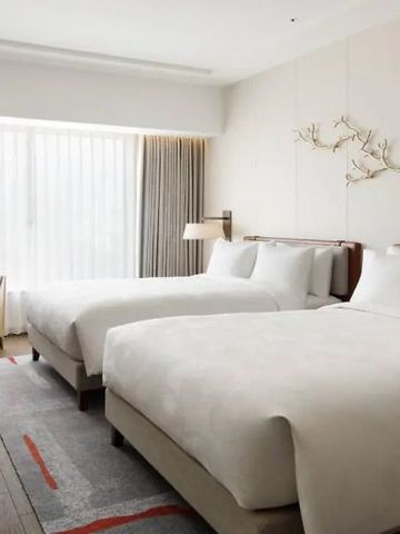 Modernes Hotelzimmer mit zwei Doppelbetten, elegantem Design und großem Fenster