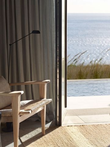 Eleganter Lounge-Bereich mit Blick auf das Meer durch eine offene Verandatür
