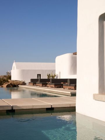 Infinity-Pool mit weißer Villa im Hintergrund und klarem Himmel