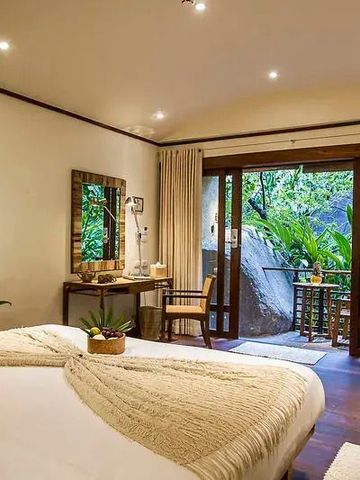 Elegantes Zimmer mit Holzmöbeln und Zugang zu einem Balkon im Grünen