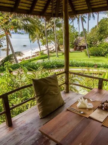 Veranda mit Blick auf grünen Garten und Ozean im Hintergrund.