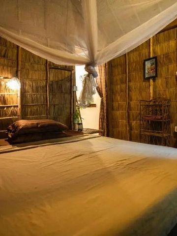 Gemütliche Hütte mit Strohwänden und Moskitonetz über dem Bett