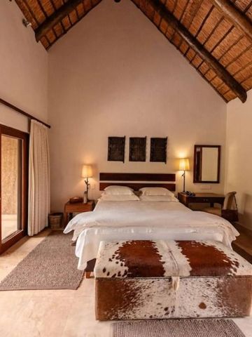 Elegantes Schlafzimmer mit hohen Decken und Holzbalken im Kapama Southern Camp