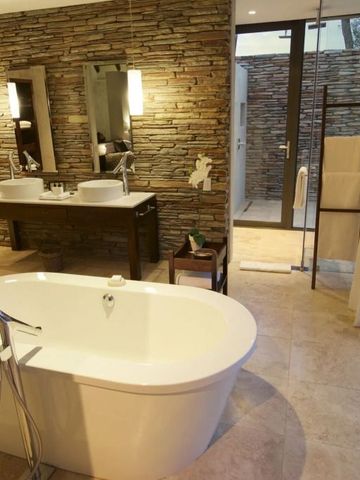 Geräumiges Badezimmer mit freistehender Badewanne und Ziegelwand