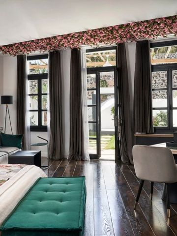 Geräumiges Hotelzimmer mit blumigen Vorhängen und Gartenblick
